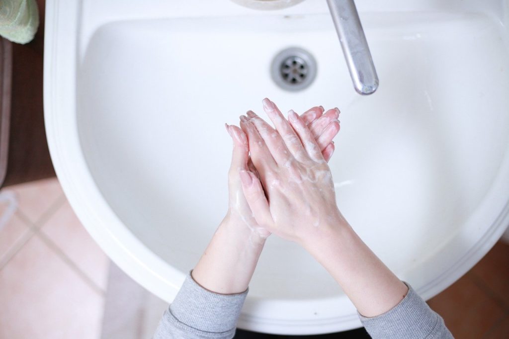 真っ白な洗面台と手を洗う誰か