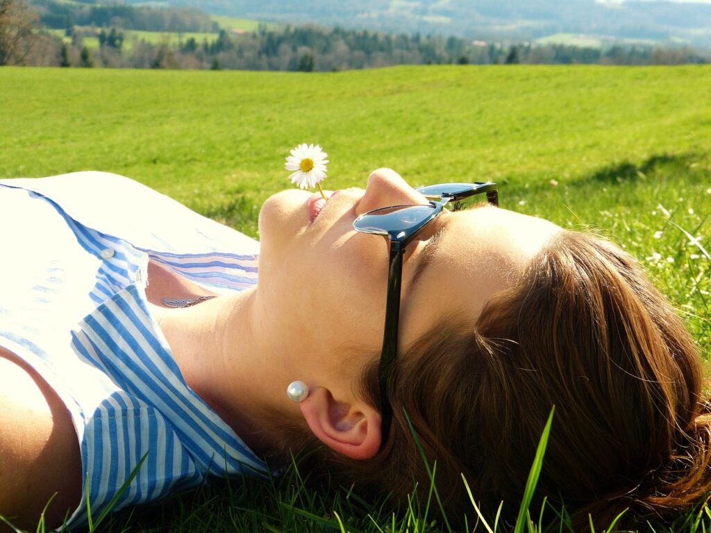 小さな花をくわえて芝生に寝そべる女性